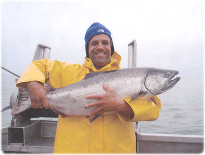 [Gene standing on a fishing boat holding a giant salmon]